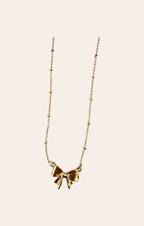 Gold bow pendant necklace with dangling bow charm on a fine chain