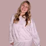 Woman wearing a light gray sweatshirt and pants against a beige background